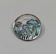 A Scottish Pat Cheney circular enamel brooch, depicting irises and reflections on a lake,