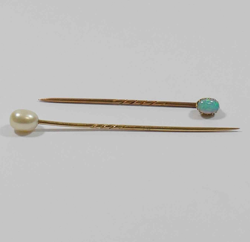 A yellow metal opal set stick pin, 5.4cm long, and a cultured pearl topped stick pin, 6.