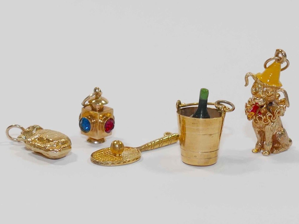 Five 9 carat gold charms, comprised of a lantern, tennis racket, koala,