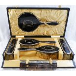 A silver and tortoiseshell backed six piece brush and mirror set comprised of a hand mirror,