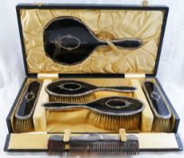 A silver and tortoiseshell backed six piece brush and mirror set comprised of a hand mirror,