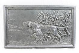 A patinated cast metal rectangular plaque depicting a gun dog amongst bull rushes,