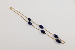 A yellow metal and lapis lazuli necklace, the chain interspersed with six lapis lazuli oval beads,