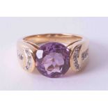 A modern 9ct yellow gold ring with tension set amethyst and diamond detail on the shoulders,