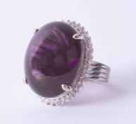 A white metal cluster ring set large Amethyst cabochon surrounded by small diamonds, stamped YK10