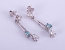 A pair contemporary 18ct white gold bar drop earrings set with enhanced blue and white diamonds.