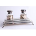 A silver continental ink and pen desk top stand on four splayed scroll feet, ink bottles with hinged