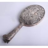 A foreign silver hand mirror with heavily embossed back and handle, replacement mirror required,