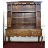 An oak dresser of Georgian design, in two sections, the upper part with open shelves and