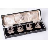 A boxed set four Geo V silver menu holders, depicting fish, dogs and fisherman, the cased marked '