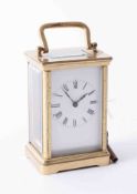 Antique brass carriage clock with white enamel face and black roman numeral markings, antique hands,