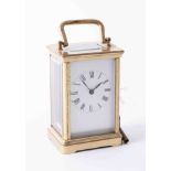 Antique brass carriage clock with white enamel face and black roman numeral markings, antique hands,