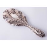 A silver hand mirror with heavy embossed scroll and ribbed decoration, mirror in good condition,