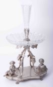 A silver plated table centrepiece, with glass fittings, decorated with vines, grapes, cherubs,