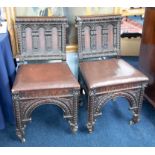 Two heavily carved dark oak side chairs.