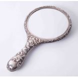 An ornate silver backed hand mirror richly embossed with winged cherubs and stylised flowers, 28cm