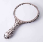 An ornate silver backed hand mirror richly embossed with winged cherubs and stylised flowers, 28cm