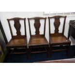 A set of carved oak dining chairs with hard seats.