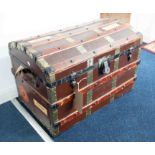 An old cabin trunk, dome top with some shipping labels and fitted with a tray.