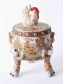 A Japanese Satsuma box and cover with cockerel finial and figure legs, height 21cm.