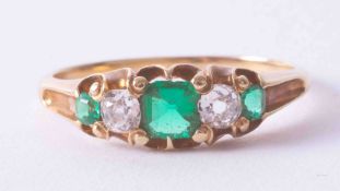 An Edwardian yellow gold five stone ring set emeralds and old cut diamonds, the central square cut
