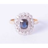 An 18ct yellow gold cluster style ring, set approx. 0.55 carats of dark blue sapphire, surrounded by