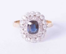 An 18ct yellow gold cluster style ring, set approx. 0.55 carats of dark blue sapphire, surrounded by