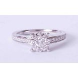 An 18ct white gold diamond set cluster ring with diamonds to the shoulders, finger size M.