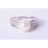 A modern 18ct white gold ring set cultured pearl, approx. 12mm, with small diamonds set to the