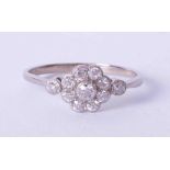 An antique 18ct white gold diamond flower cluster ring with milgrain setting, finger size S.