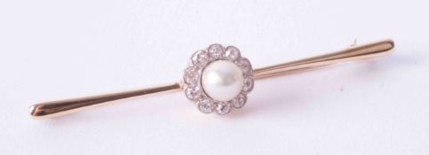 An antique yellow gold bar brooch set with a cultured pearl and surrounded by diamonds in the