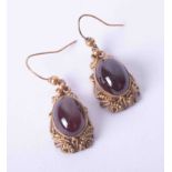 A pair of Continental ornate style yellow gold earrings set cabochon almandine garnets with hook ear