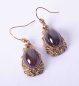 A pair of Continental ornate style yellow gold earrings set cabochon almandine garnets with hook ear