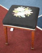 An early 20th Century mahogany framed stool on tapered legs with spade feet and tapestry