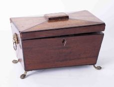 A mahogany tea caddy of sarcophagus style on brass feet.