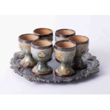 A set of six Doulton art pottery egg cups with silver mounts (some damage).