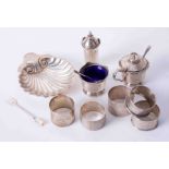 Five assorted silver napkin rings, a silver and scallop shell butter dish and a three piece silver