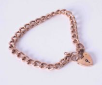 A 9ct rose gold curb link bracelet with heart padlock and safety chain, weight 23g.