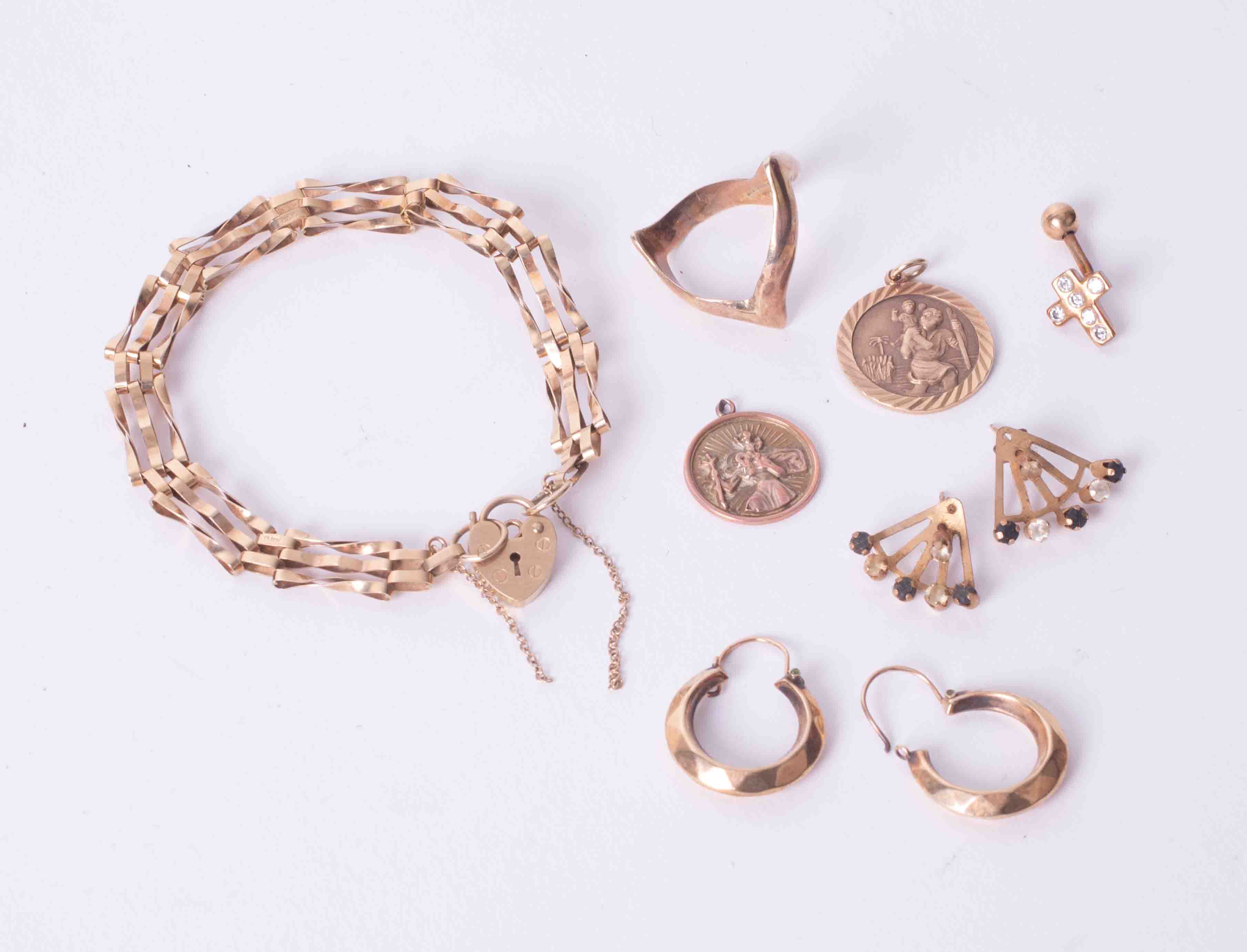 A bag of mixed 9ct jewellery items to include a wishbone ring, heart padlock gate link bracelet,