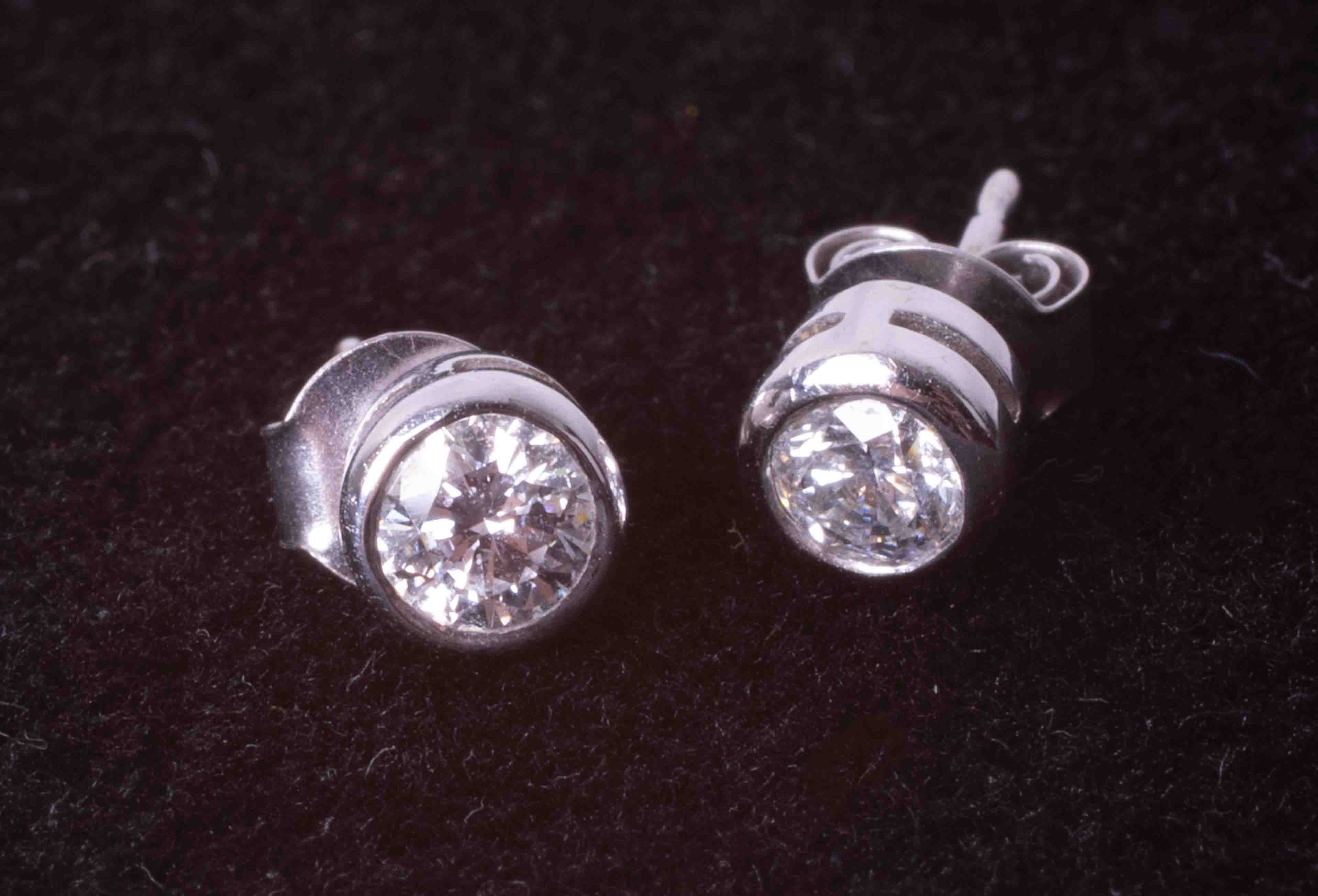 A pair of modern 9ct white gold rub-over round brilliant cut diamond set earrings with post &