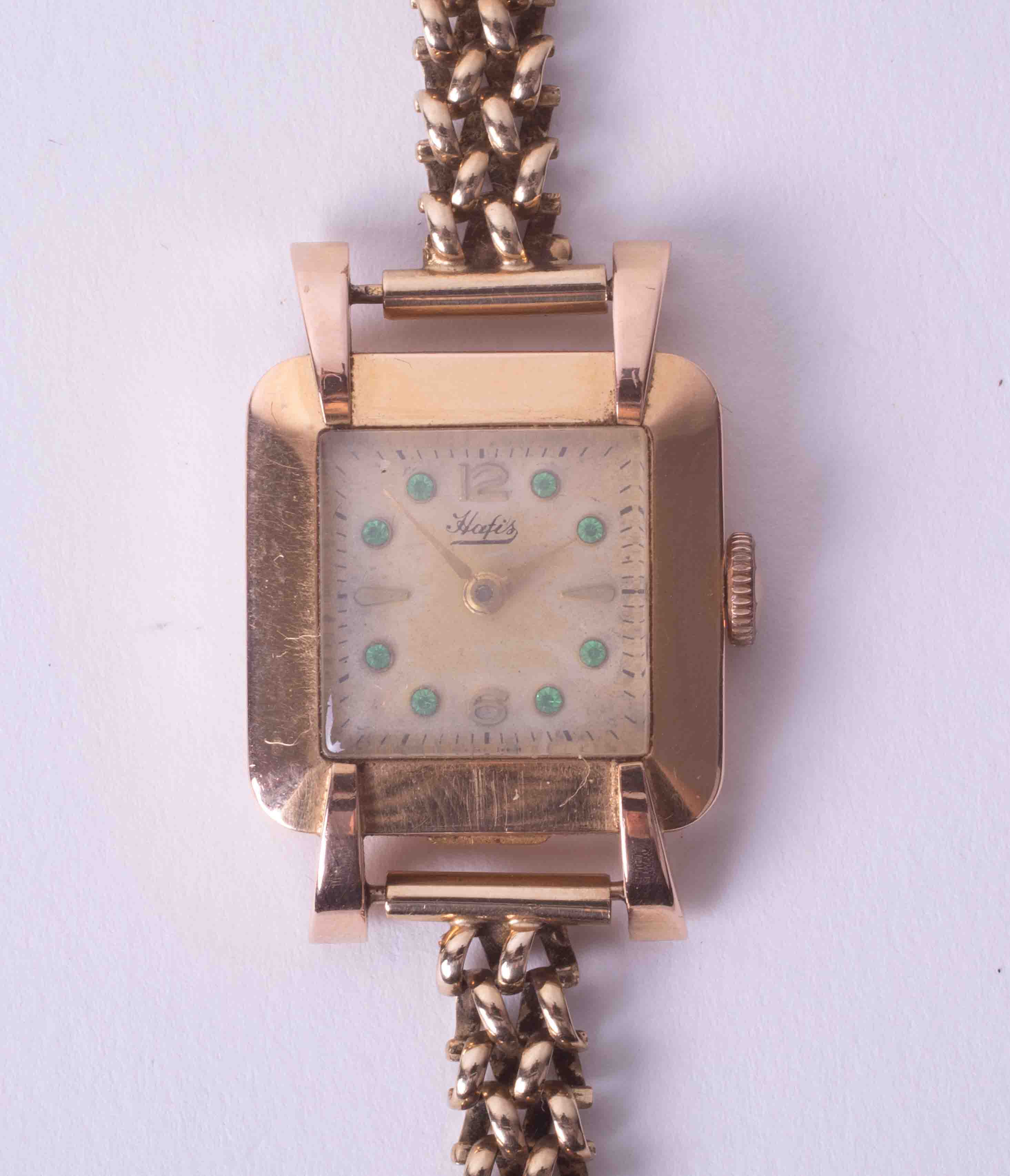 An 18k yellow gold ladies 'Hafis' wristwatch with green stones set to the dial, approx 17.6g.