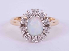 An 18ct yellow & white gold cluster ring set with an oval cabochon cut white opal measuring