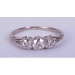 An antique platinum three stone rub over set ring with approx. 0.60 carats total weight of old cut