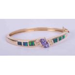 A 14k yellow gold bangle set centrally with two interlocking trilliant cut tanzanite's, approx. 1.40