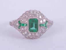 A platinum Art Deco style ring set central emerald cut emerald, approx. 0.55 carats surrounded by