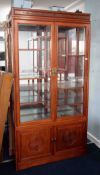 A modern Chinese style rosewood display cabinet, fitted with two glazed doors enclosing an