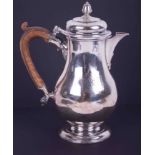 A Georgian silver coffee pot of baluster shape with a faded crest and crest to the lid, acorn