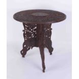 An Anglo Indian carved hardwood table (in two pieces with folding base, label Ganoomals Curios).