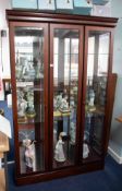 A modern freestanding two door display cabinet, fitted with glass shelves, mirror interior and