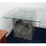 A modern glass top coffee table on a faux stone base, height 54cm, width of glass 69cm.